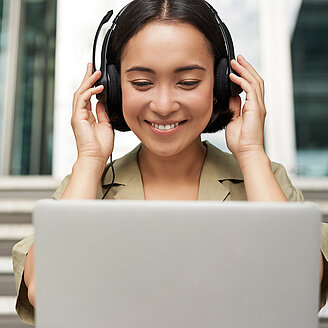 RKW Campus – © benzoix / Freepik Das Foto zeigt eine junge Frau, die mit einem Laptop auf einer Treppe sitzt.