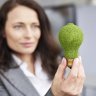 © gpointstudio | Freepik – © gpointstudio / Freepik Das Foto zeigt eine Frau, die eine mit Moos bewachsene Glühbirne hochhält.